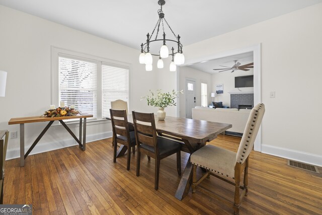 dining room with hardwood / wood-style floors, baseboards, a tiled fireplace, and visible vents