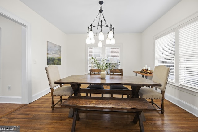 dining area featuring dark wood finished floors, plenty of natural light, baseboards, and an inviting chandelier