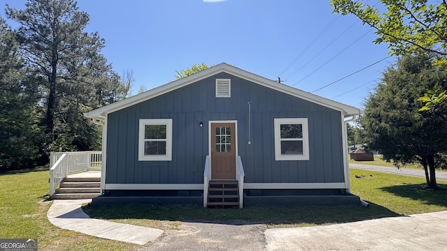 view of front facade with board and batten siding, entry steps, and a front yard