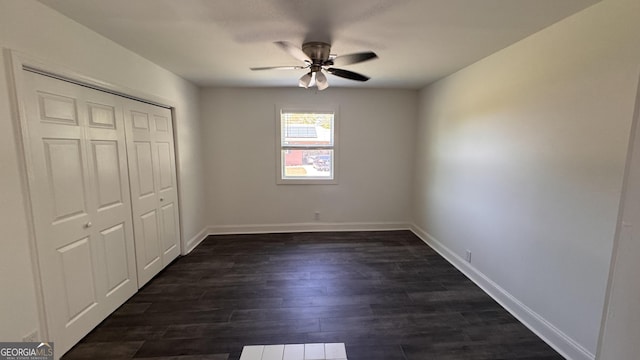 unfurnished bedroom with ceiling fan, baseboards, dark wood-style floors, and a closet