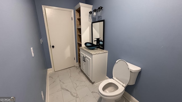 bathroom featuring marble finish floor, baseboards, toilet, and a sink