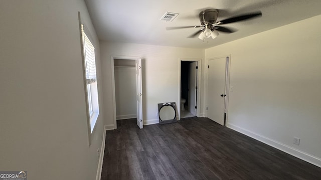 unfurnished bedroom with a closet, dark wood finished floors, visible vents, and baseboards