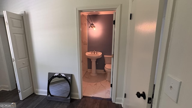 hall featuring dark wood finished floors, baseboards, and a sink