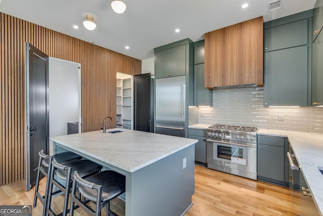 631 Bent Grass, Clayton, GA 30525 - kitchen with premium appliances, backsplash, green cabinets, a center island with sink, and light wood-type flooring