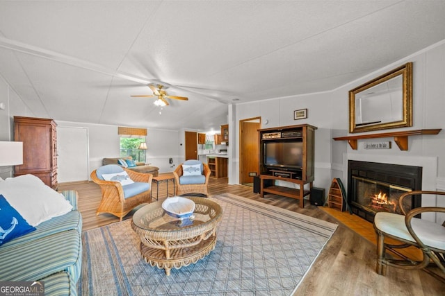 82 Dogwood Ct, Sparta, GA 31087 - living room featuring vaulted ceiling, a ceiling fan, a glass covered fireplace, and wood finished floors