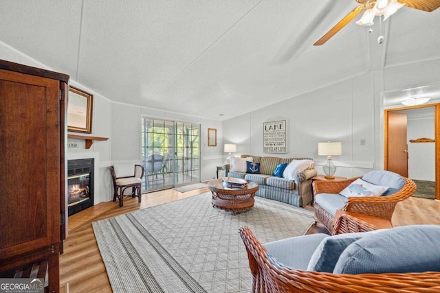 82 Dogwood Ct, Sparta, GA 31087 - living area with ceiling fan, lofted ceiling, a glass covered fireplace, and light wood-style flooring