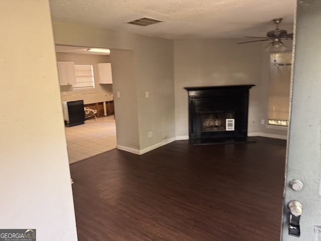 3260 Rivermist Cv, Decatur, GA 30034 - unfurnished living room with a ceiling fan, dark wood-style flooring, a textured ceiling, a fireplace with raised hearth, and baseboards