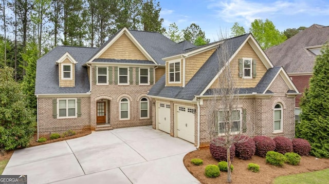 craftsman-style home featuring a garage, driveway, brick siding, and roof with shingles