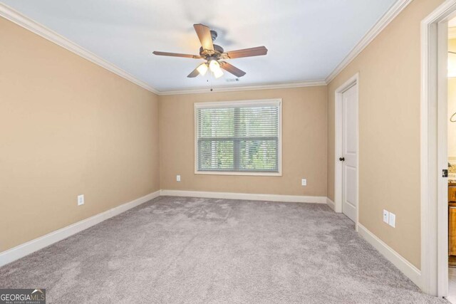carpeted empty room with ceiling fan, baseboards, and crown molding