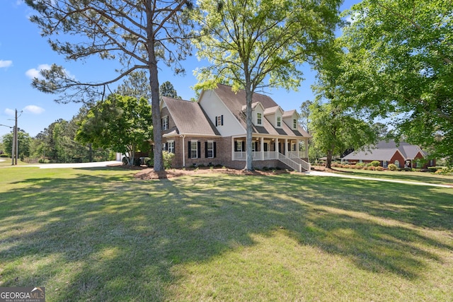 cape cod house featuring brick siding, covered porch, and a front yard