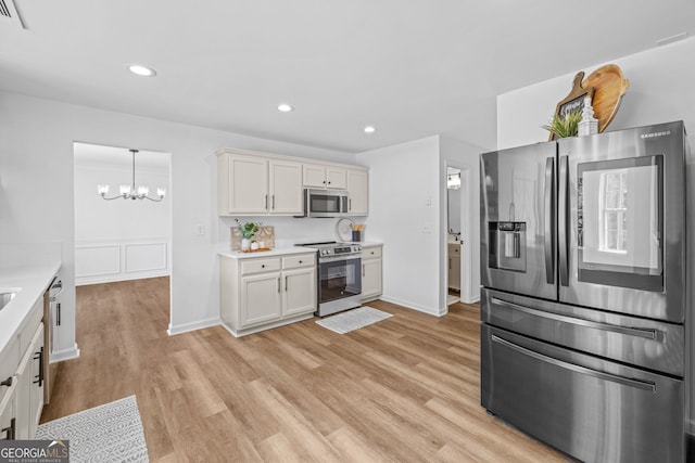 24 Hamilton Dr, Jefferson, GA 30549 - kitchen with light countertops, appliances with stainless steel finishes, light wood finished floors, white cabinetry, and a notable chandelier