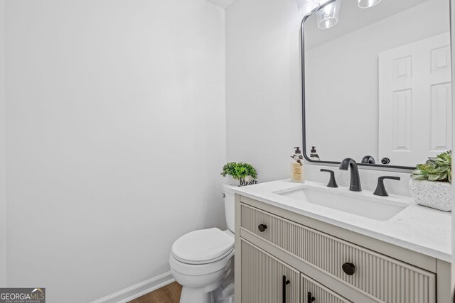 24 Hamilton Dr, Jefferson, GA 30549 - half bath featuring baseboards, wood finished floors, vanity, and toilet