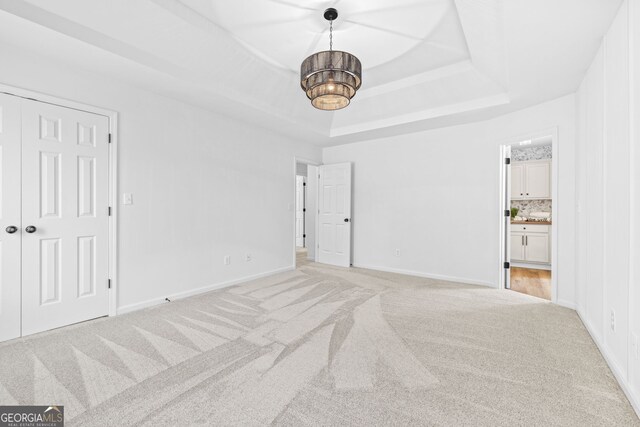 24 Hamilton Dr, Jefferson, GA 30549 - unfurnished bedroom featuring ensuite bathroom, baseboards, a notable chandelier, light colored carpet, and a raised ceiling