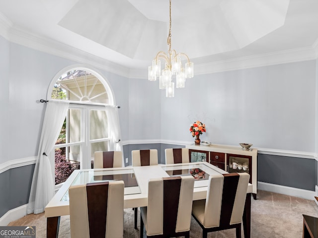 carpeted dining area featuring a raised ceiling, ornamental molding, baseboards, and a notable chandelier