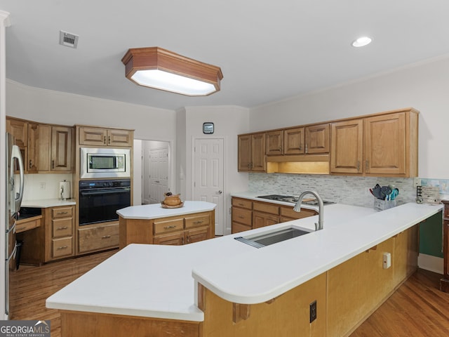 kitchen with appliances with stainless steel finishes, a sink, visible vents, and wood finished floors