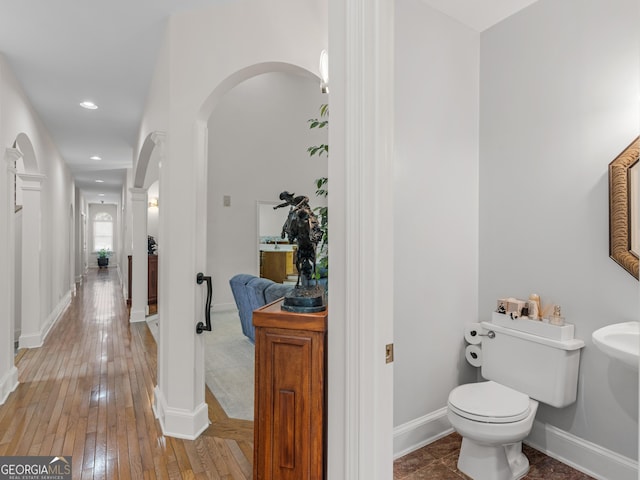 half bath featuring recessed lighting, baseboards, wood-type flooring, and toilet