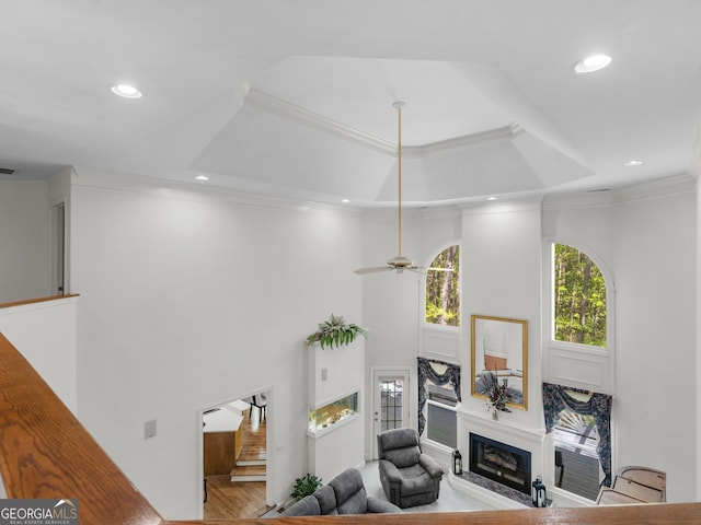 living area with a fireplace, wood finished floors, a high ceiling, ornamental molding, and recessed lighting