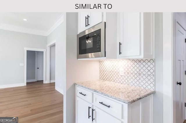 104 Reedy Ct, Perry, GA 31069 - kitchen featuring built in microwave, ornamental molding, light wood-style floors, white cabinetry, and decorative backsplash