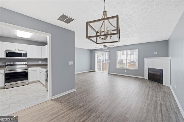 720 Georgetown Ln, Jonesboro, GA 30236 - unfurnished living room with a tiled fireplace, visible vents, light wood-style flooring, and ceiling fan