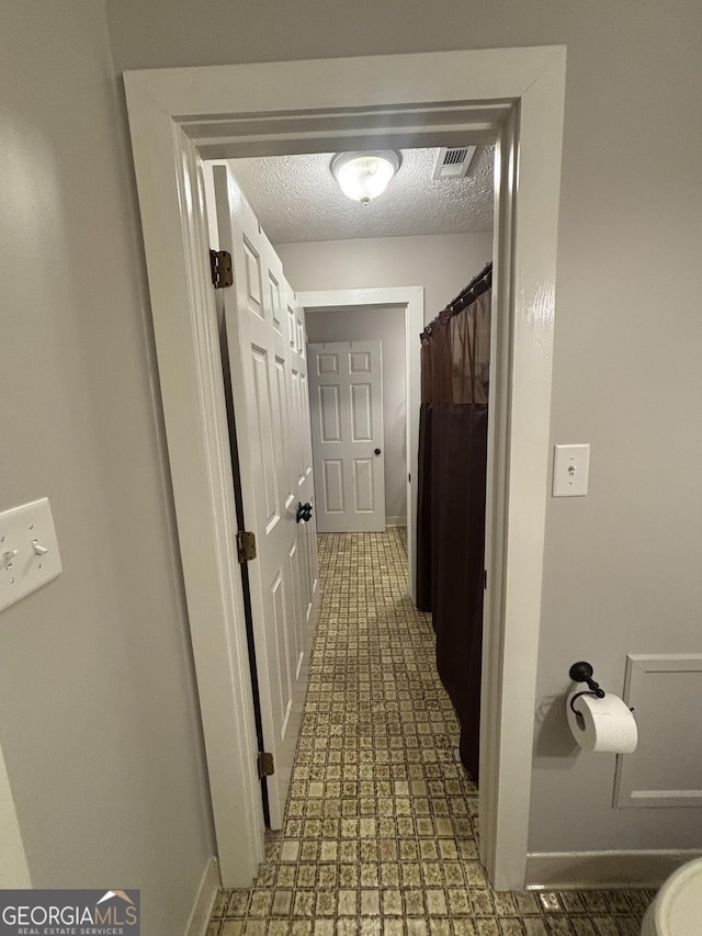 hall with a textured ceiling and baseboards