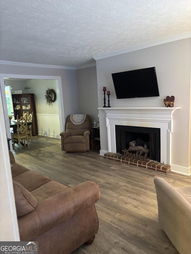 living room featuring wood finished floors, a brick fireplace, crown molding, a textured ceiling, and baseboards