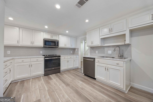 6101 River Rd Apt 20, Columbus, GA 31904 - kitchen with white cabinets, light wood-style flooring, a sink, baseboards, and appliances with stainless steel finishes