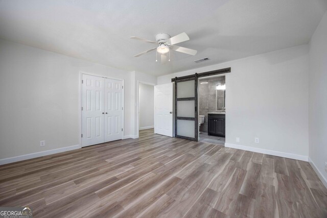 6101 River Rd Apt 20, Columbus, GA 31904 - unfurnished bedroom featuring a barn door, wood finished floors, visible vents, and baseboards
