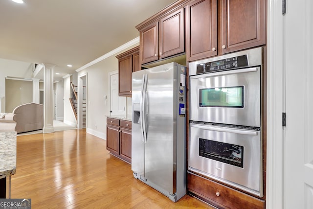 kitchen featuring light wood-style flooring, light stone countertops, ornamental molding, and stainless steel appliances