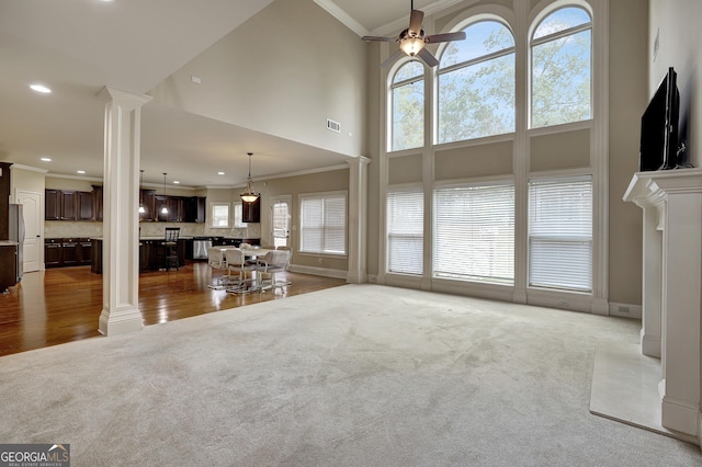 unfurnished living room with crown molding, carpet floors, decorative columns, a towering ceiling, and recessed lighting