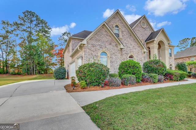 french provincial home with brick siding, a front lawn, driveway, and a garage