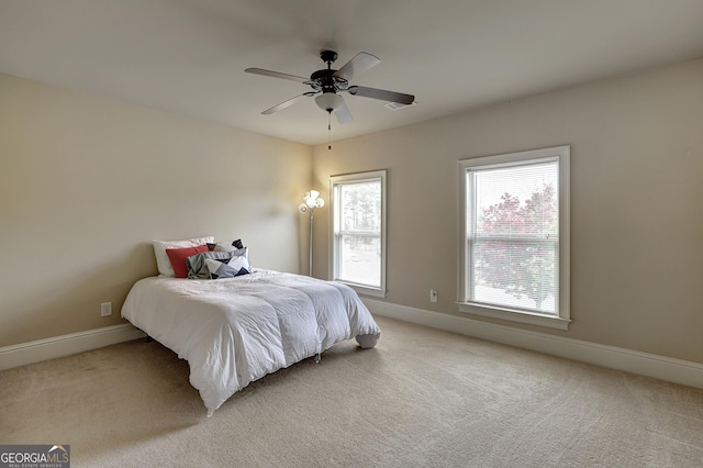 bedroom with light carpet, a ceiling fan, visible vents, and baseboards