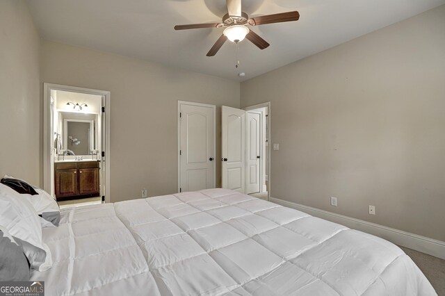 bedroom featuring ensuite bath, baseboards, carpet, and a ceiling fan