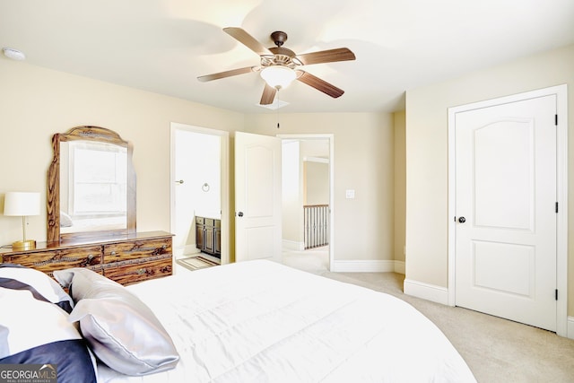 bedroom featuring baseboards, light colored carpet, ceiling fan, and connected bathroom