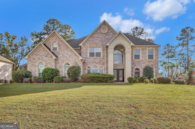 traditional-style home featuring french doors, brick siding, and a front yard