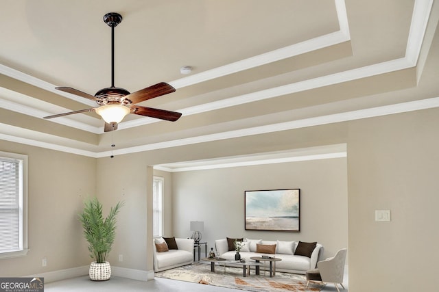 living area with baseboards, a ceiling fan, ornamental molding, and a raised ceiling