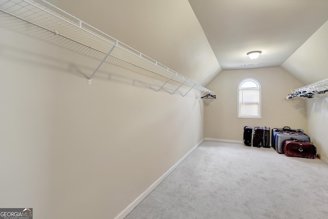 walk in closet with carpet floors and lofted ceiling