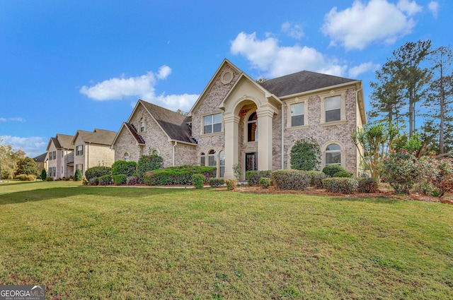 french country inspired facade featuring brick siding and a front yard