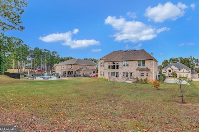 back of property with brick siding, a yard, and fence