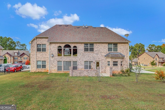 back of house featuring a lawn and brick siding