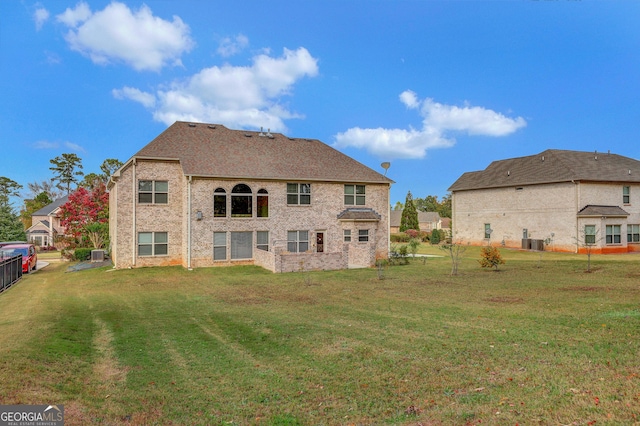 back of property featuring a lawn, brick siding, central air condition unit, and fence