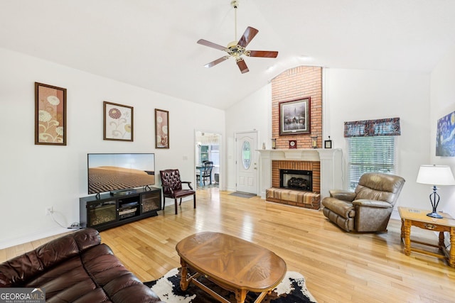 living area featuring high vaulted ceiling, a ceiling fan, light wood finished floors, and a fireplace