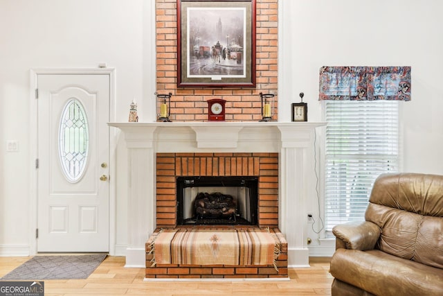 living room featuring baseboards, a brick fireplace, wood finished floors, and a healthy amount of sunlight