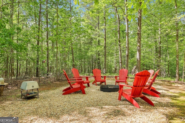 exterior space featuring a fire pit and a view of trees