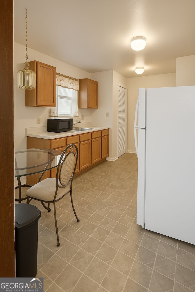 3272 Kingston Rd, Atlanta, GA 30318 - kitchen featuring brown cabinets, black microwave, light countertops, baseboards, and freestanding refrigerator