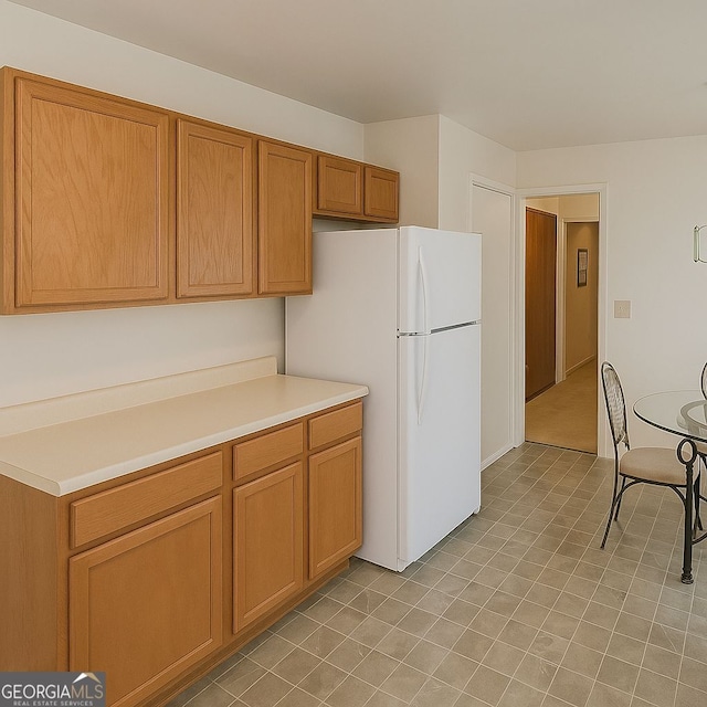 3272 Kingston Rd, Atlanta, GA 30318 - kitchen with brown cabinetry, light tile patterned flooring, light countertops, and freestanding refrigerator