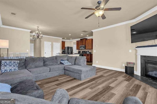 5015 Jack Dr, Decatur, GA 30035 - living room featuring dark wood finished floors, visible vents, ornamental molding, a glass covered fireplace, and ceiling fan with notable chandelier