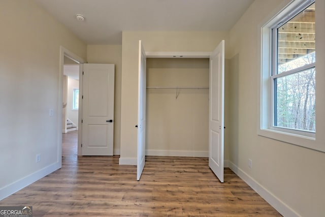 162 Forest Canopy Way, Clayton, GA 30525 - unfurnished bedroom with baseboards, multiple windows, a closet, and wood finished floors
