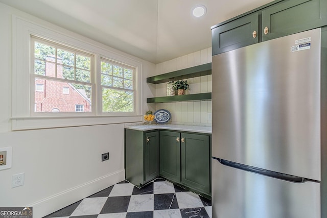 kitchen featuring green cabinetry, light countertops, open shelves, freestanding refrigerator, and baseboards