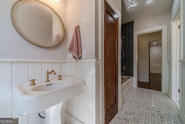 bathroom with tile patterned floors, wainscoting, a sink, and a bathtub