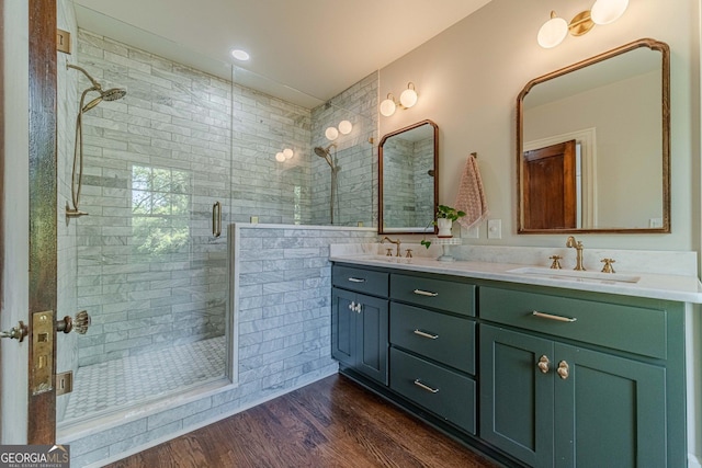 bathroom with wood finished floors, a sink, a shower stall, and double vanity